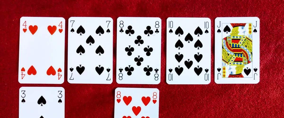 Playing cards laid out in rows on red felt